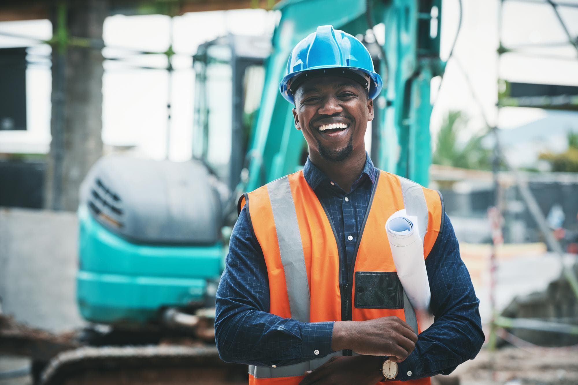 Site engineer in a hard hat and hi-vis vest holding project drawings